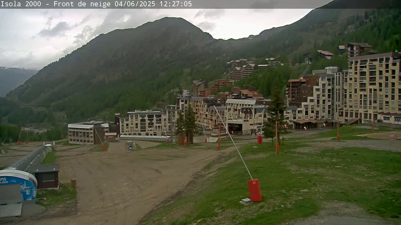 A mountainside village of multi-story buildings under a cloudy sky.