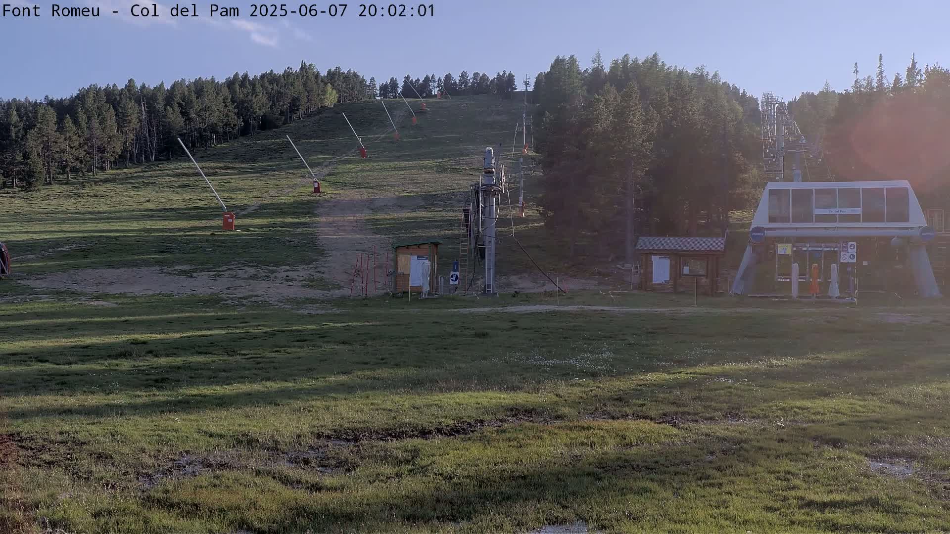 A grassy ski lift area with a chairlift and gates is visible, under a clear sky at dusk.