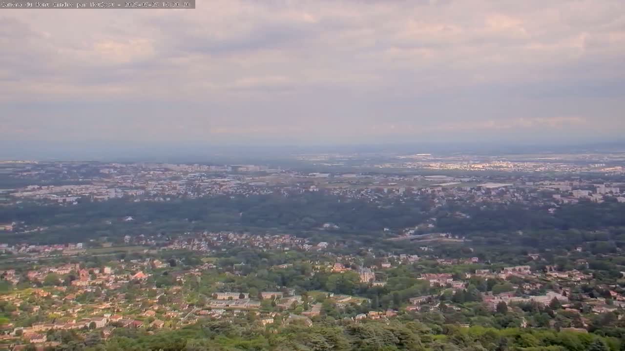 A sprawling suburban landscape extends to a hazy horizon under a partly cloudy sky.