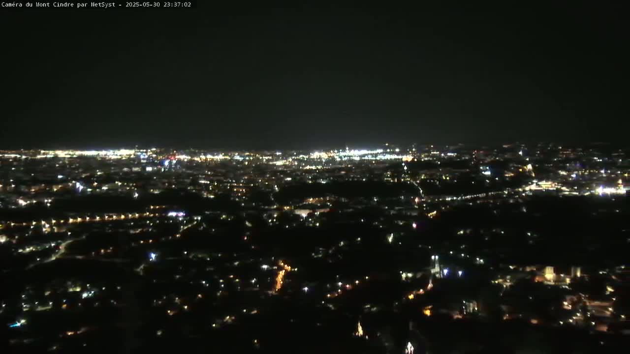 A nighttime aerial view of a sprawling city with numerous lights illuminating the landscape under a clear, dark sky.