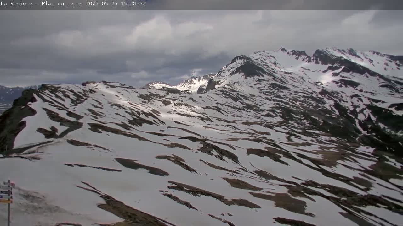 Snow-covered mountains are visible under a cloudy sky.