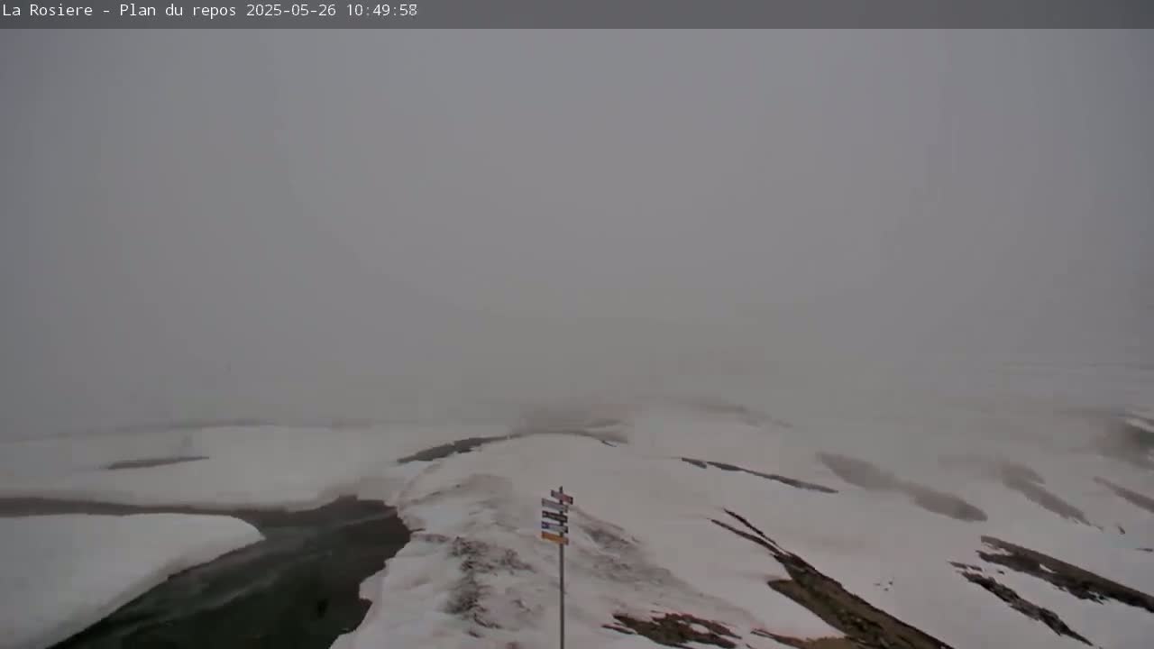 A snow-covered landscape is visible through a heavy fog.