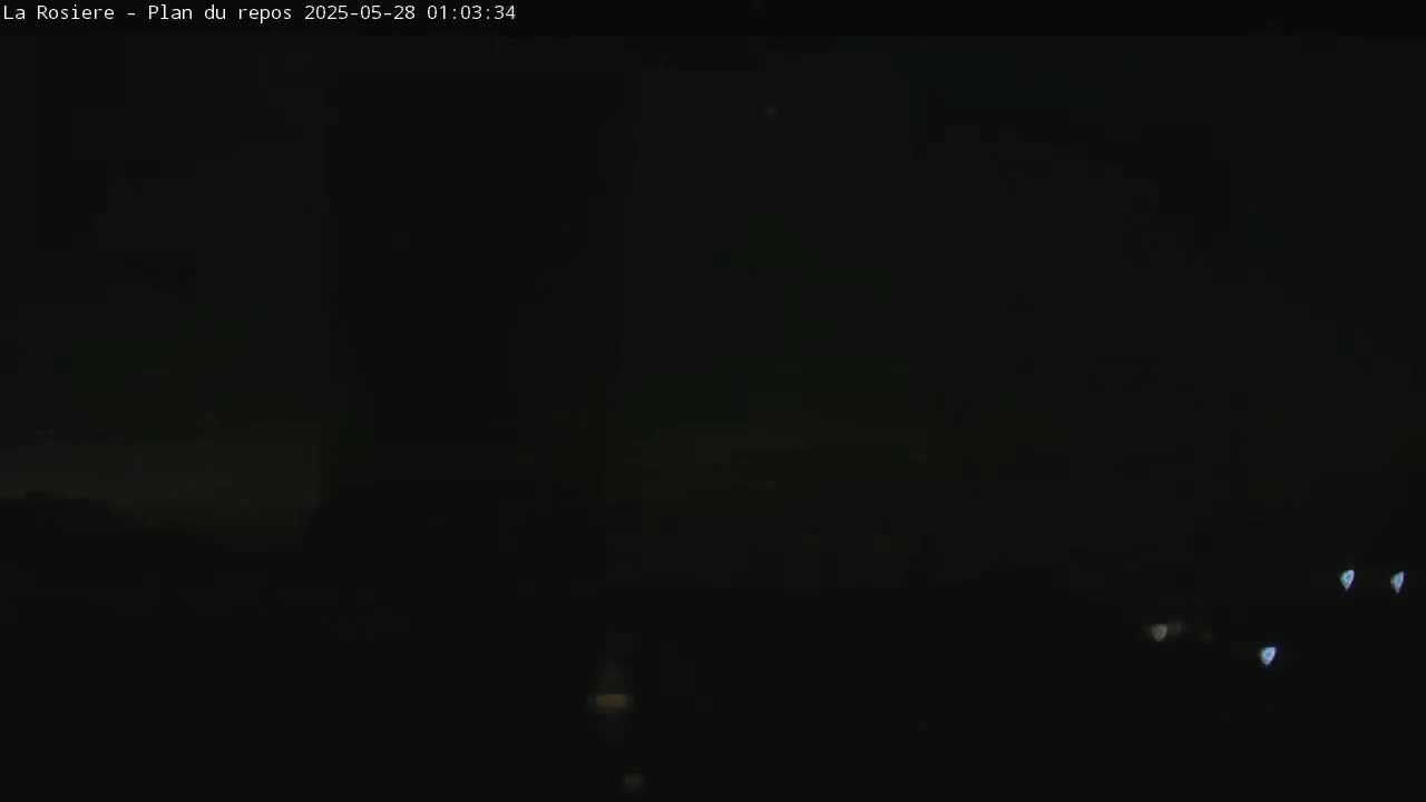 A dark, nighttime scene shows a few faint lights in the distance.