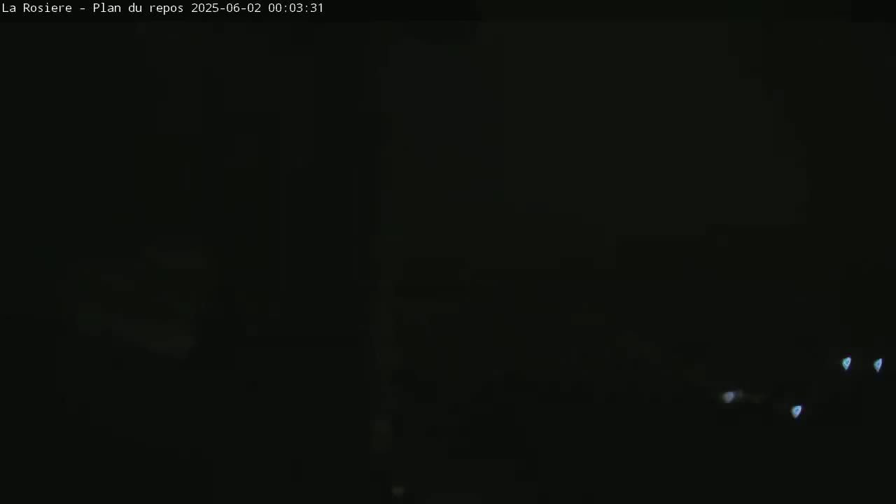 A very dark image shows a few faint lights in the distance at night.