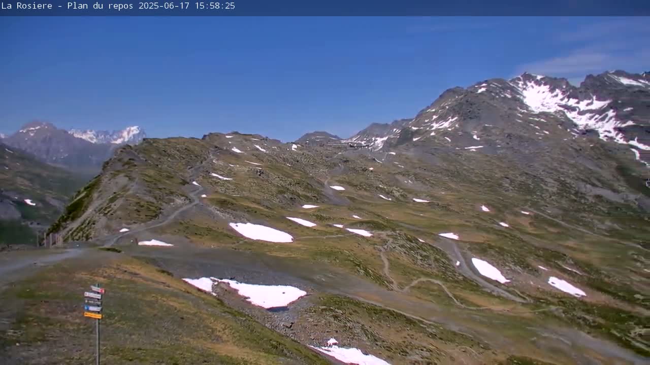 A mountain range with patches of snow under a clear blue sky.