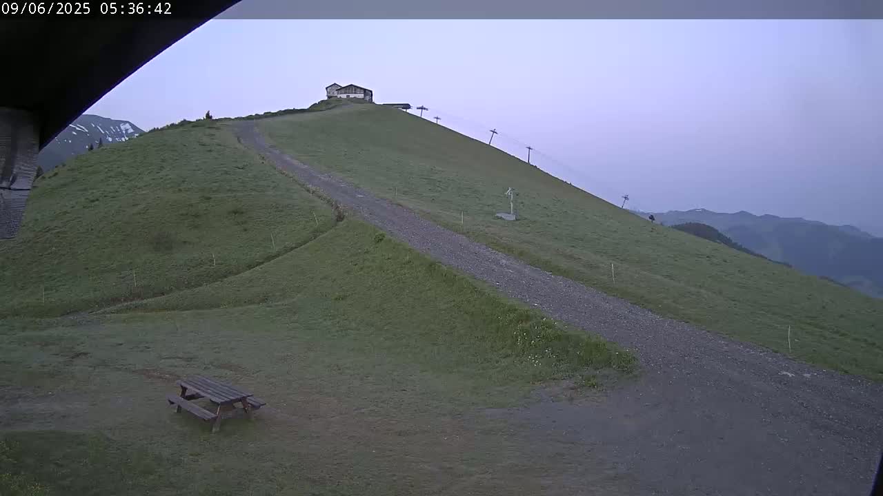 A gravel path leads up a grassy hill towards a small building under a pale, overcast sky.