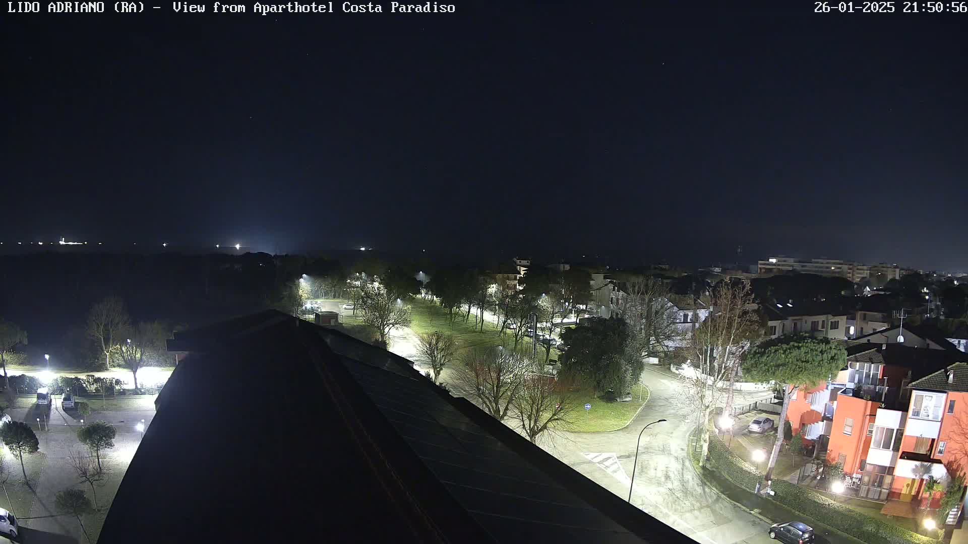 Here is a description of the image: A nighttime, high-angle view of a residential area illuminated by streetlights, under a clear, dark sky.