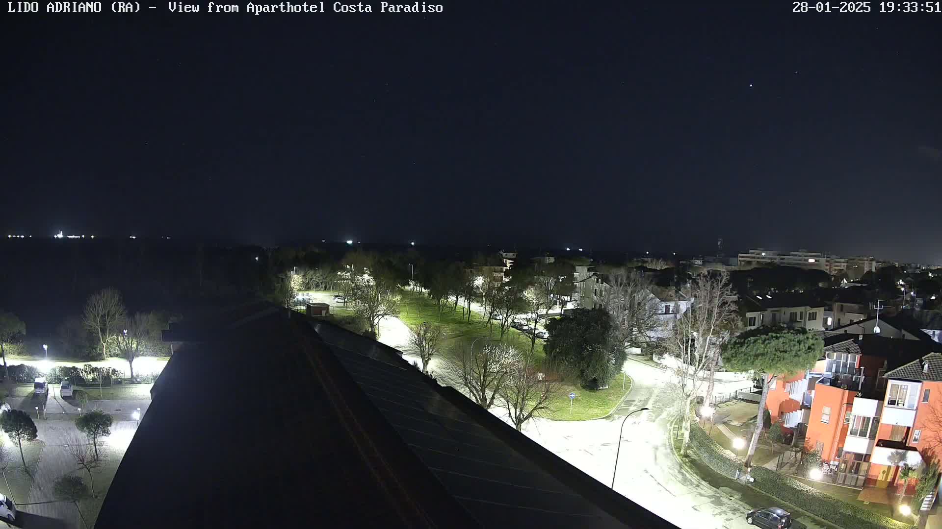 A nighttime view of a residential area with a park and curving roads, under a clear, dark sky.