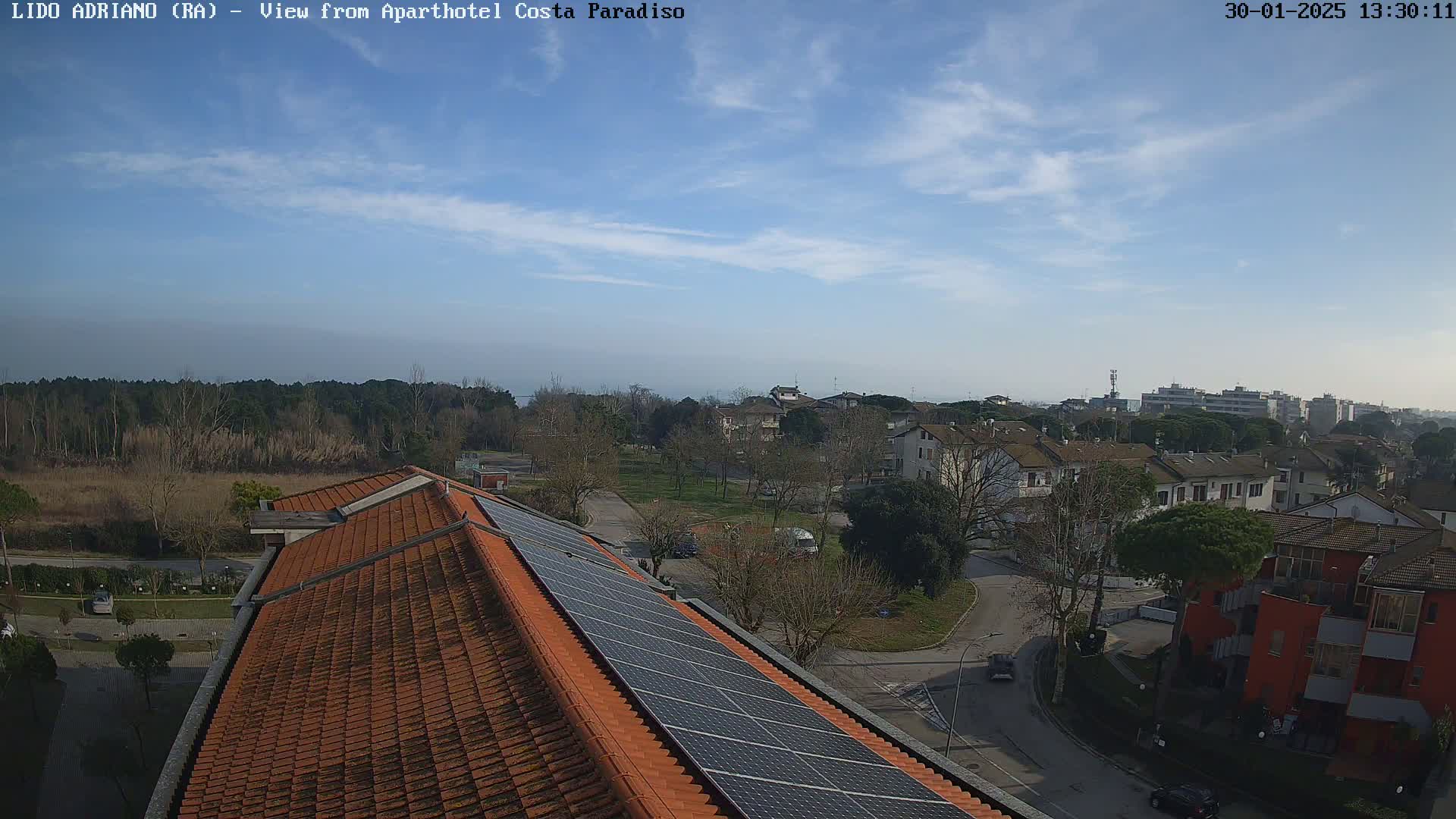 A mostly sunny day overlooking a residential area with a rooftop featuring solar panels.