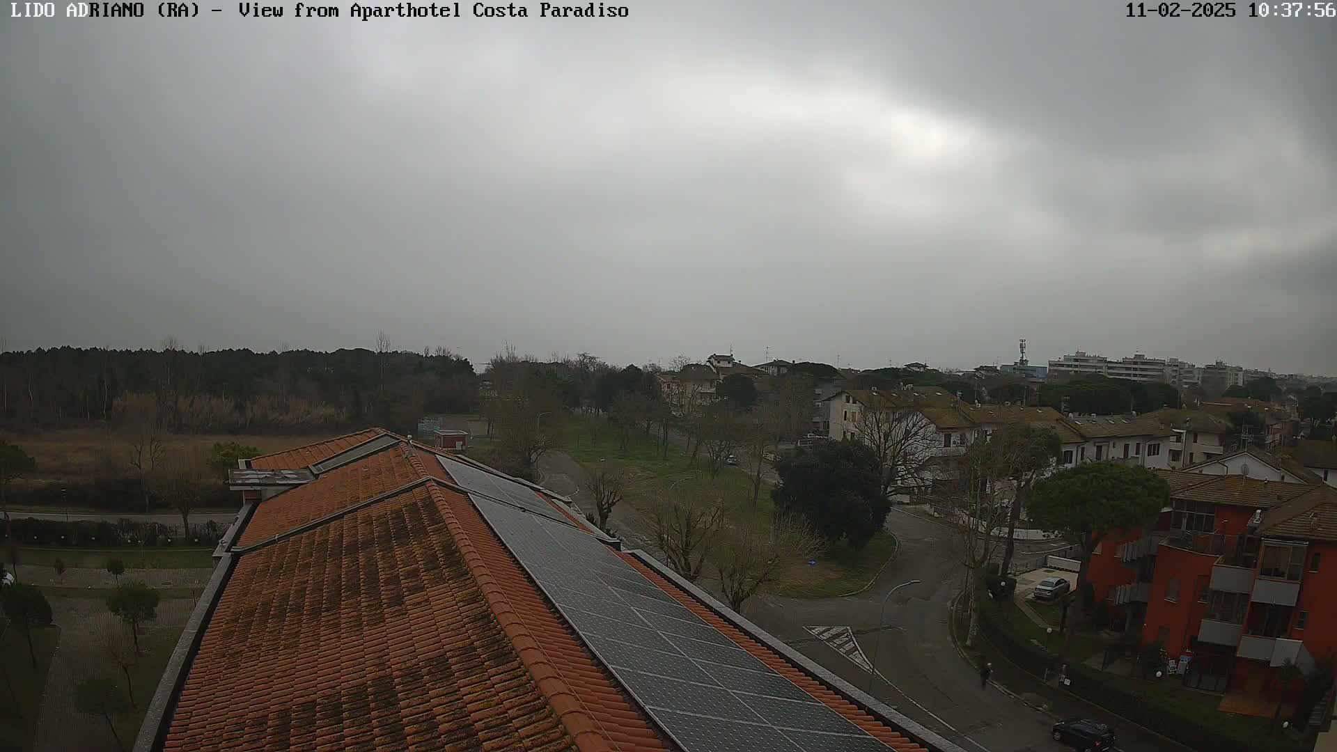 An overcast sky looks down on a residential area with a red building and a building with solar panels on its roof.