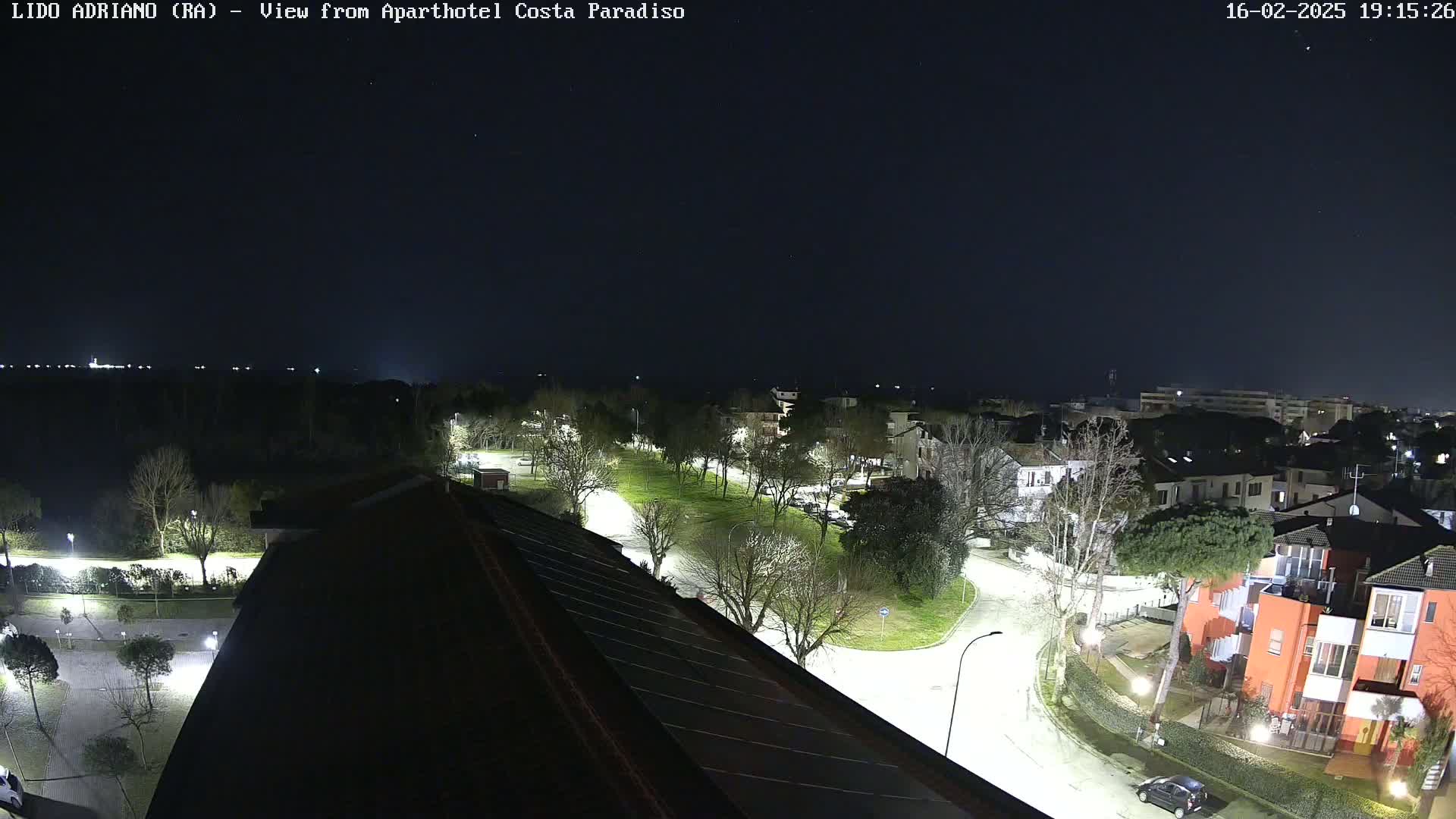 A nighttime, overhead view of a residential area with roads, trees, and buildings illuminated by streetlights.