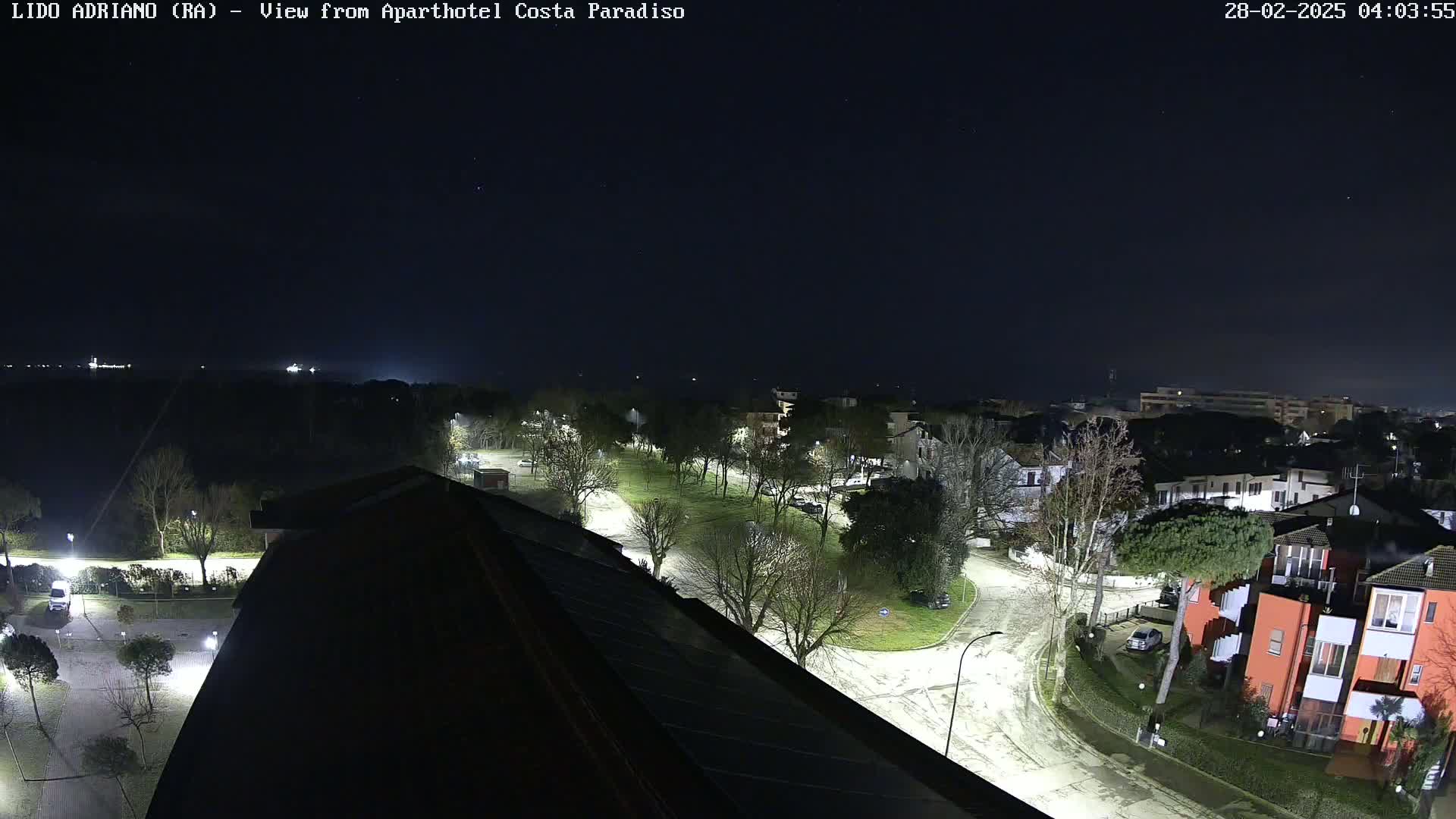 A nighttime aerial view of a residential area with snow-dusted roads and a clear, dark sky.