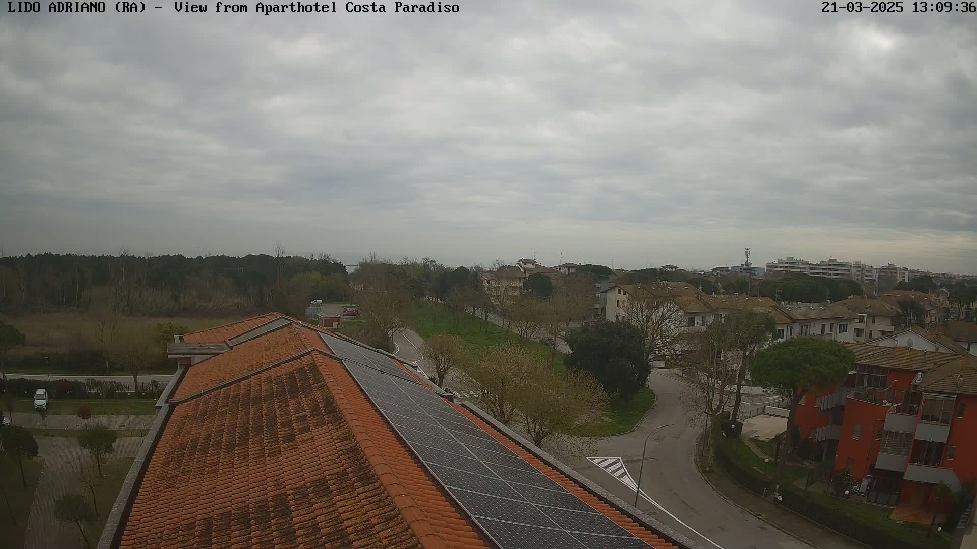 A view of a residential area on an overcast day, seen from a rooftop with solar panels.