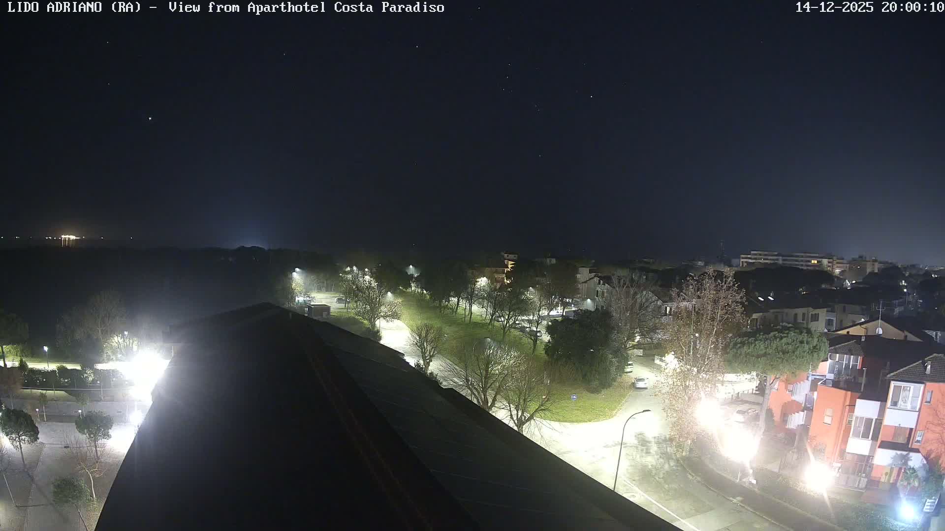 A dense fog envelops an outdoor scene from a high vantage point, revealing solar panels on a terracotta-tiled roof in the foreground, with a street, cars, and buildings dimly visible through the heavy mist.
