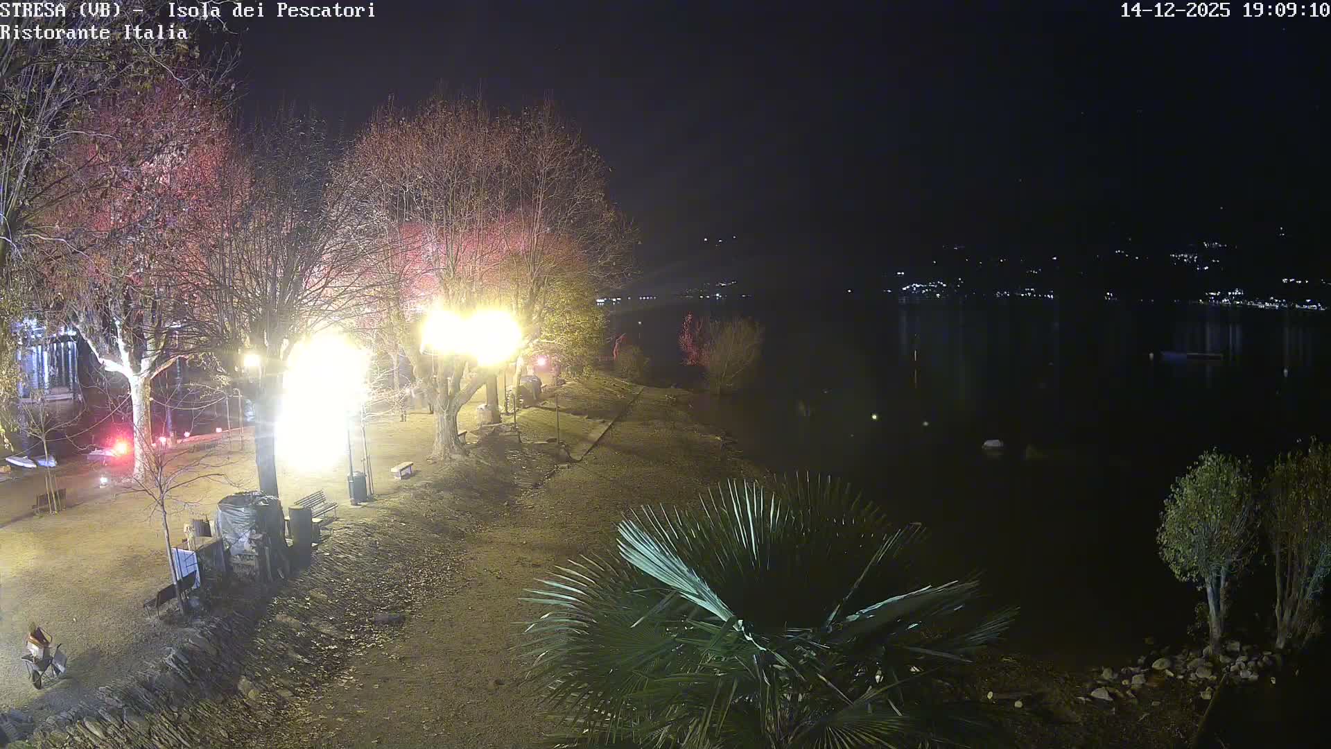A vibrant turquoise body of water lies nestled among rocky, tree-covered hills under a clear sky.