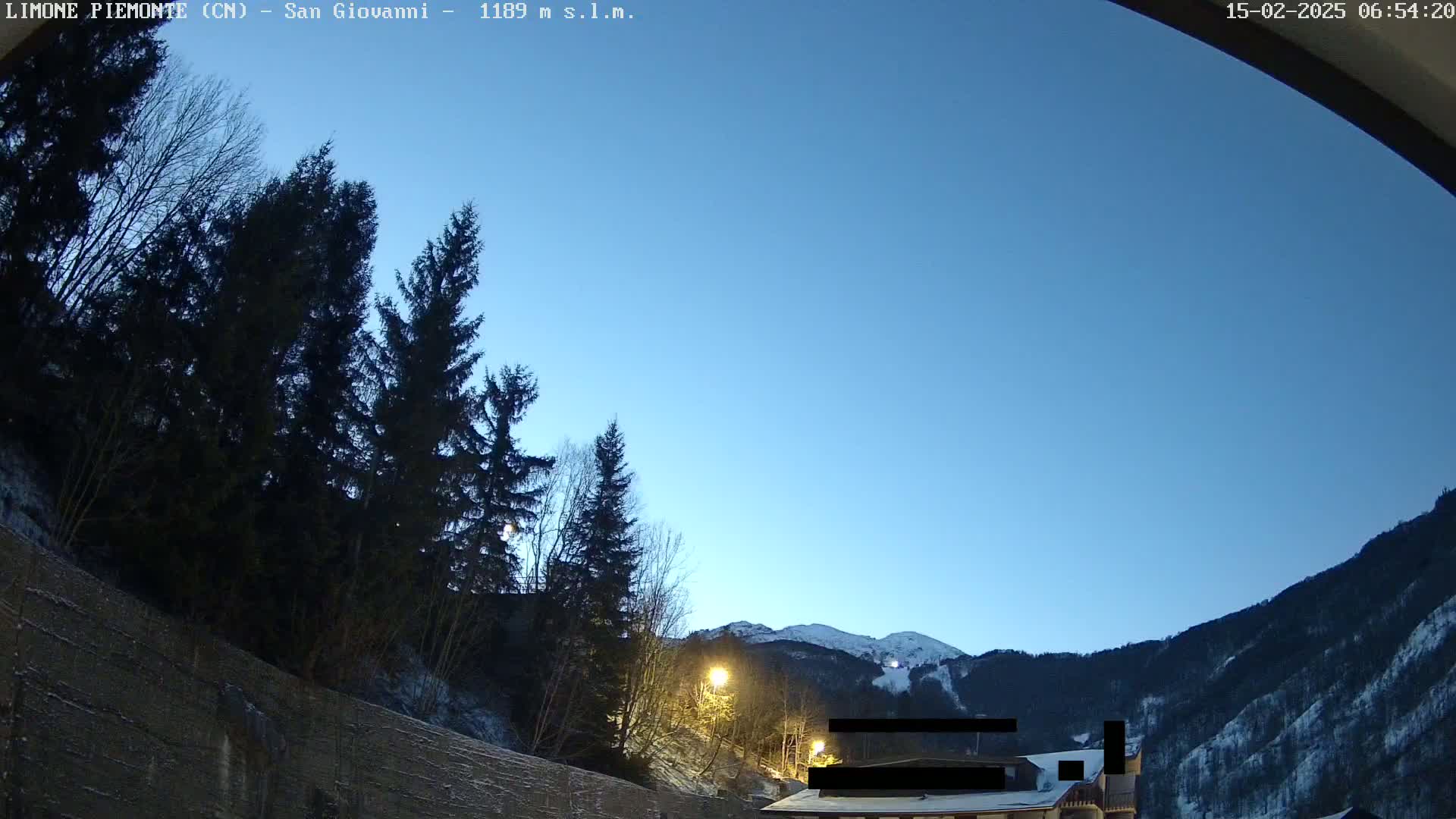 A clear, twilight sky over snow-dusted mountains and evergreens.