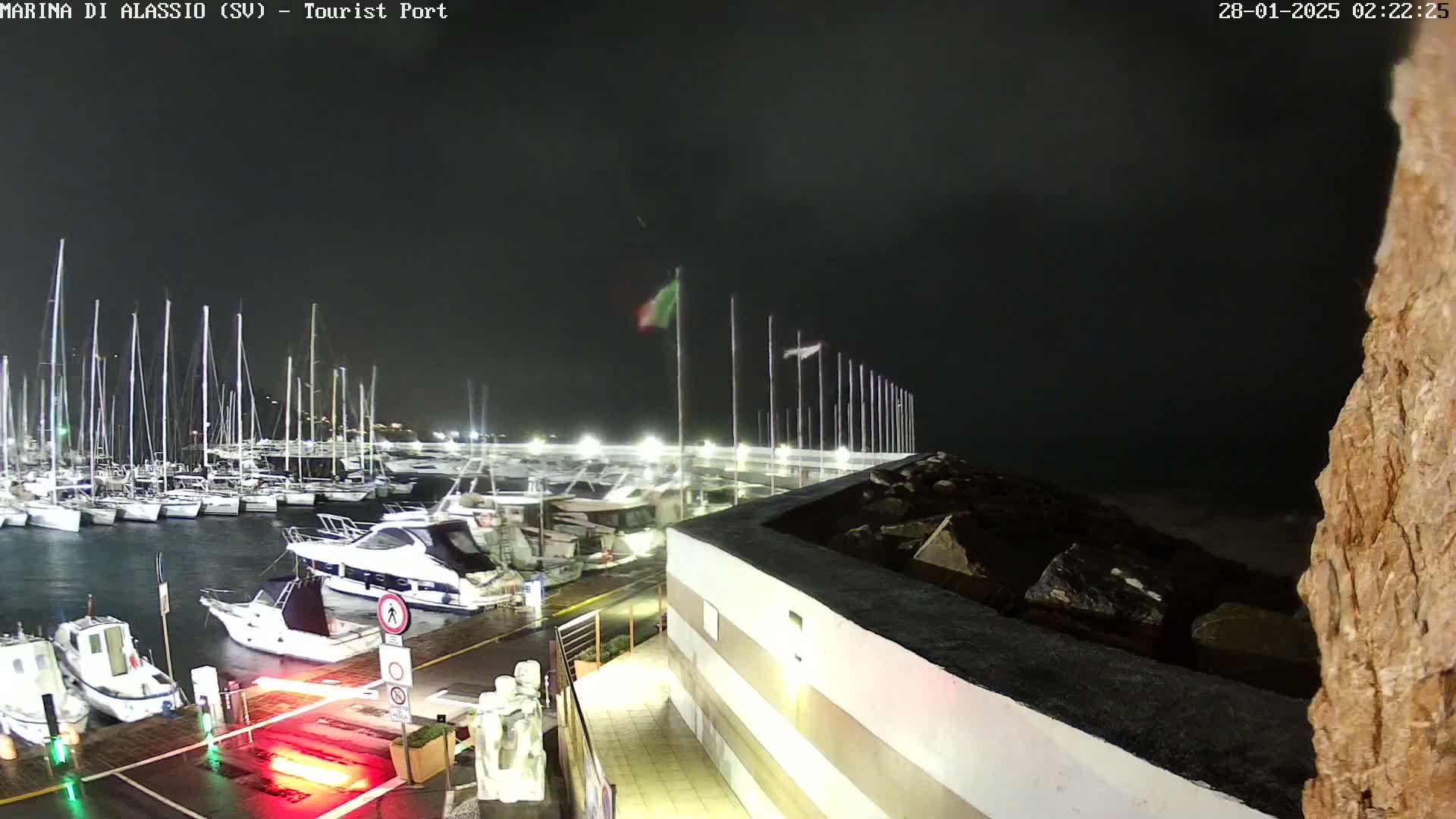 A nighttime view of a marina filled with boats under a dark, cloudy sky.
