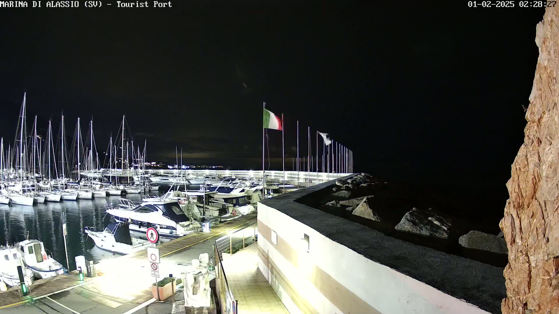A marina at night filled with sailboats and motorboats, under a dark sky.
