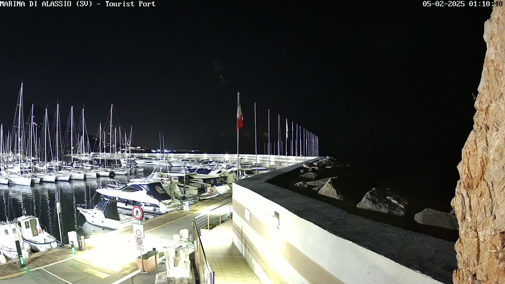 A nighttime view of a marina filled with sailboats and motorboats, under a clear, dark sky.