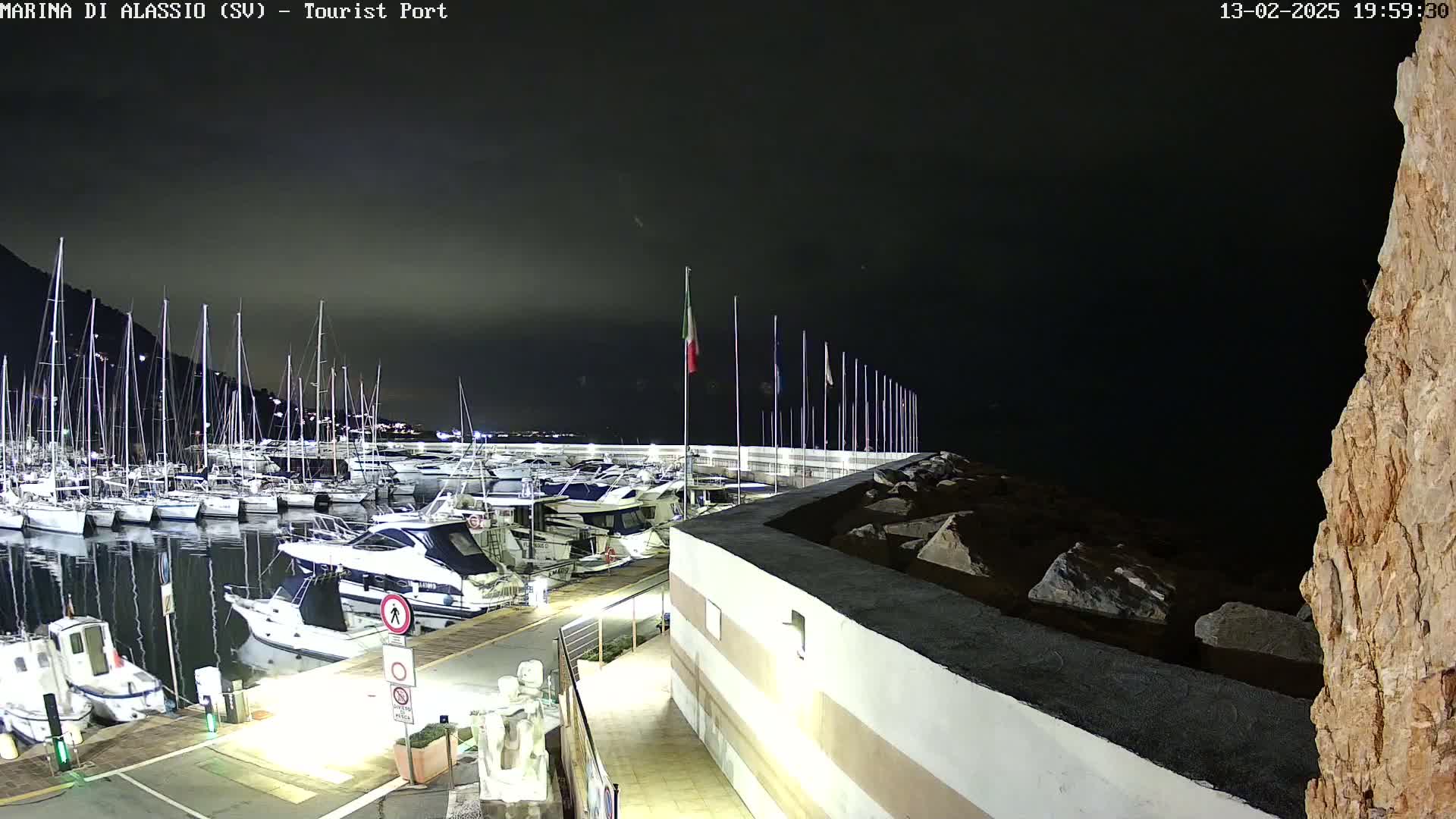 A nighttime view of a marina filled with docked boats under a dark, cloudy sky.