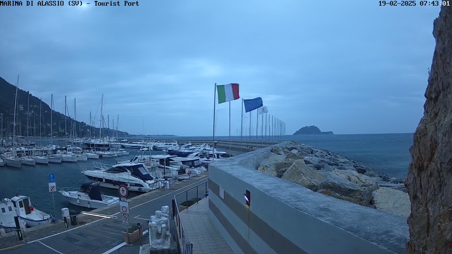 A harbor filled with sailboats and motorboats under an overcast sky.