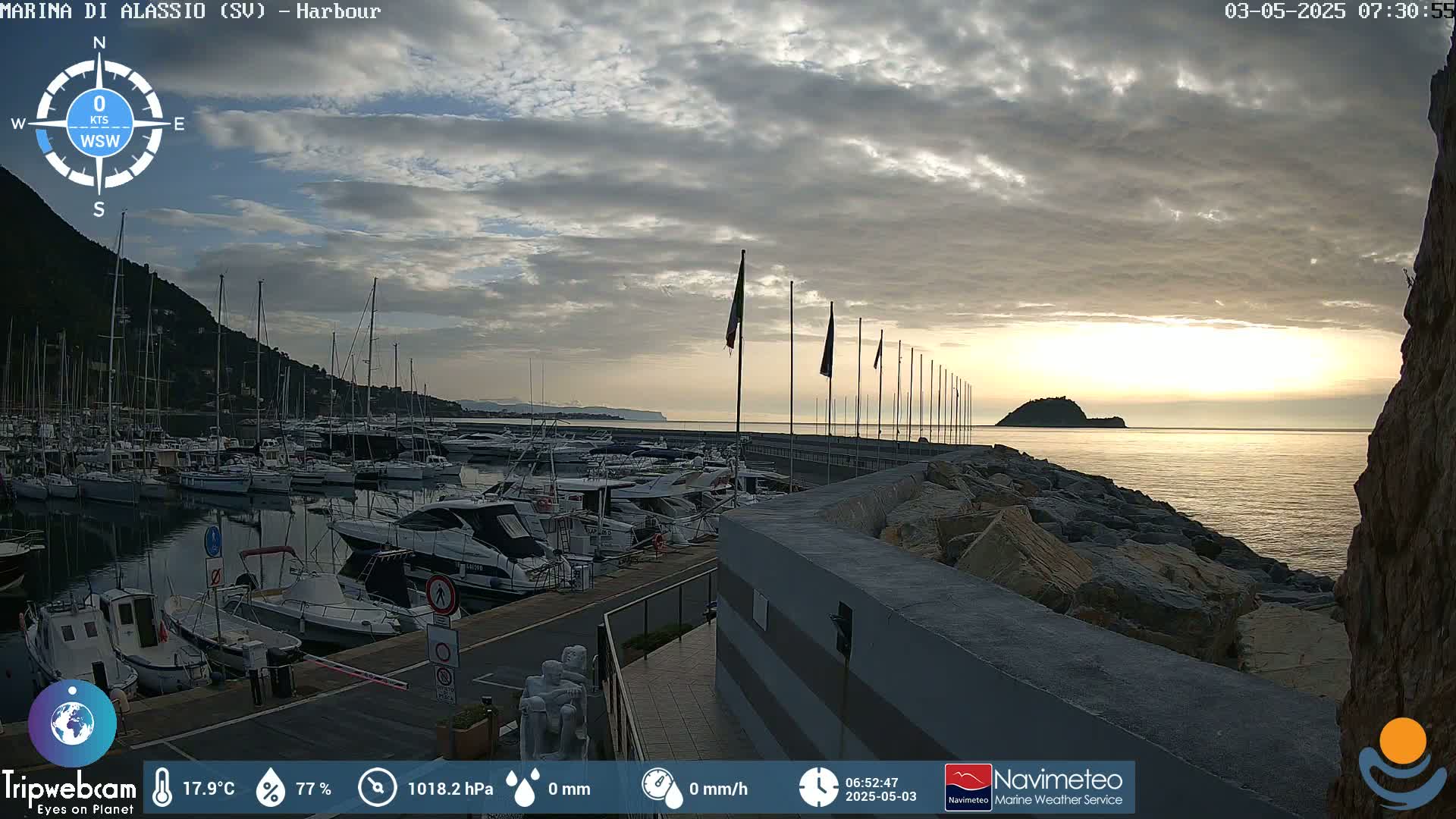A harbor filled with numerous boats is seen at sunrise under a partly cloudy sky.