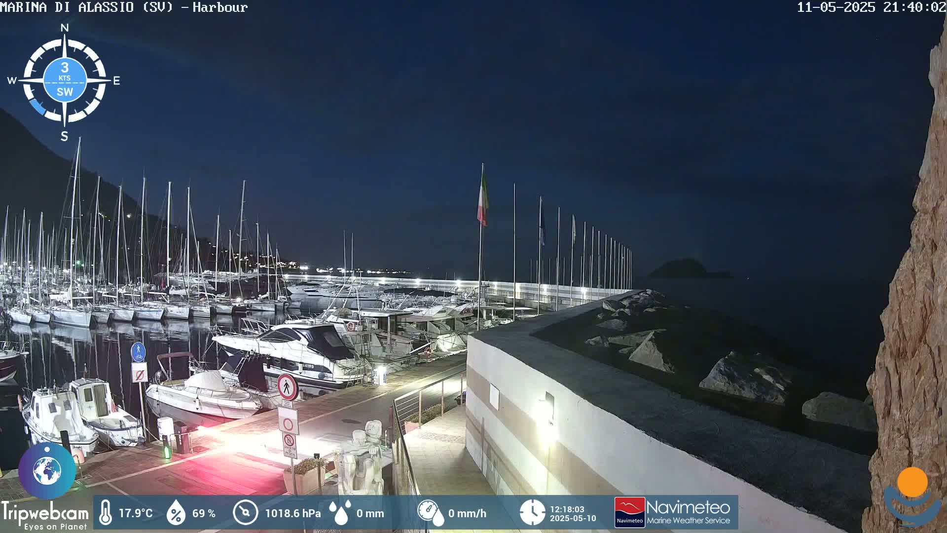 A nighttime harbor scene shows numerous boats docked, with calm water and a dark sky.
