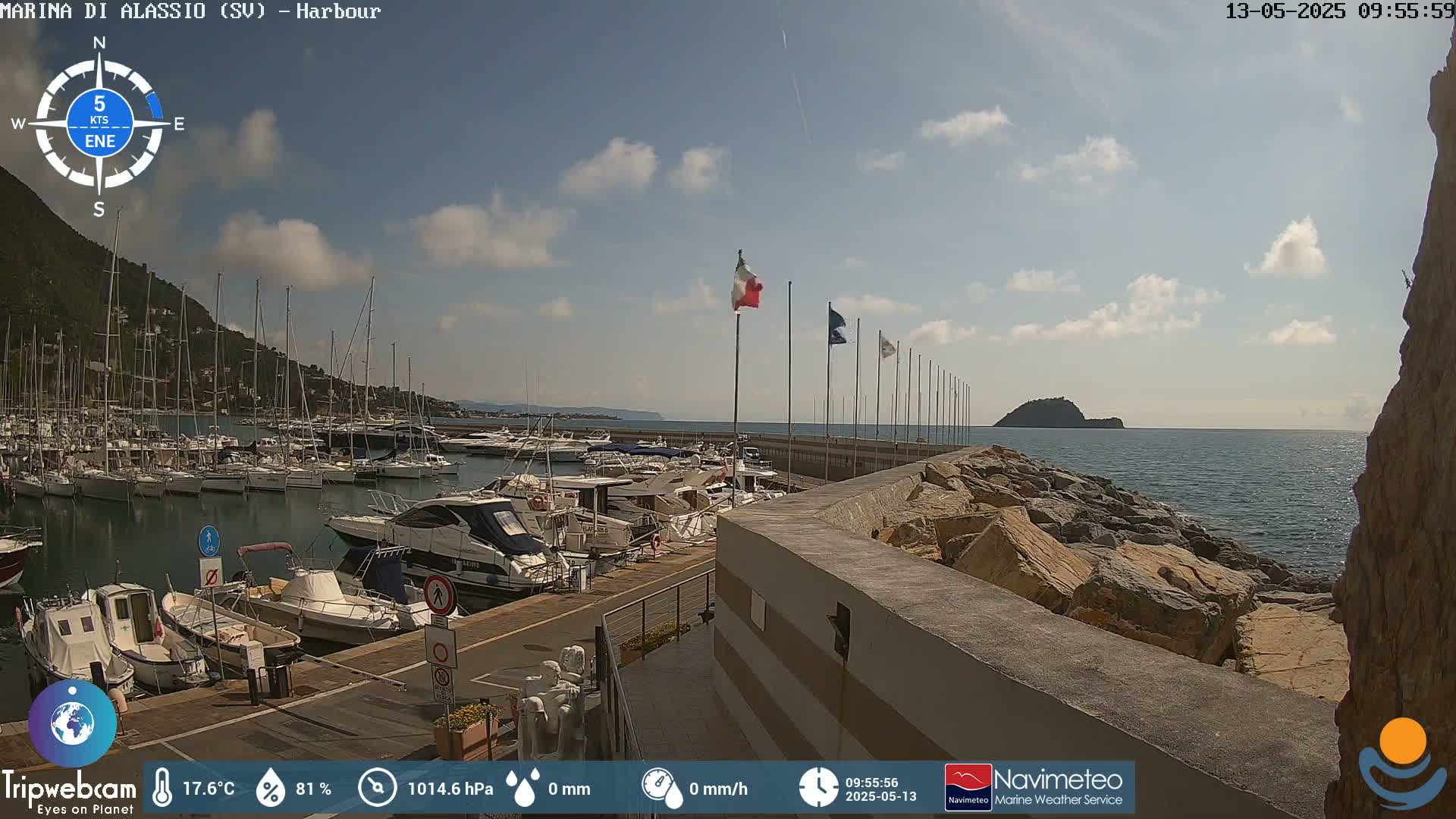 A harbor filled with boats is seen under a mostly sunny sky with some scattered clouds.