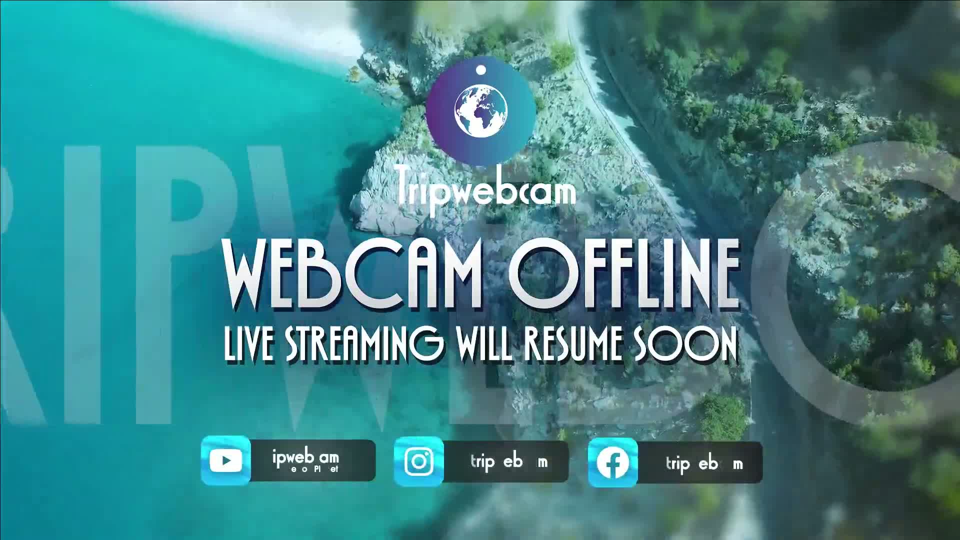 An aerial view of a rocky coastline meeting turquoise water, overlaid with a message indicating that a webcam is offline.