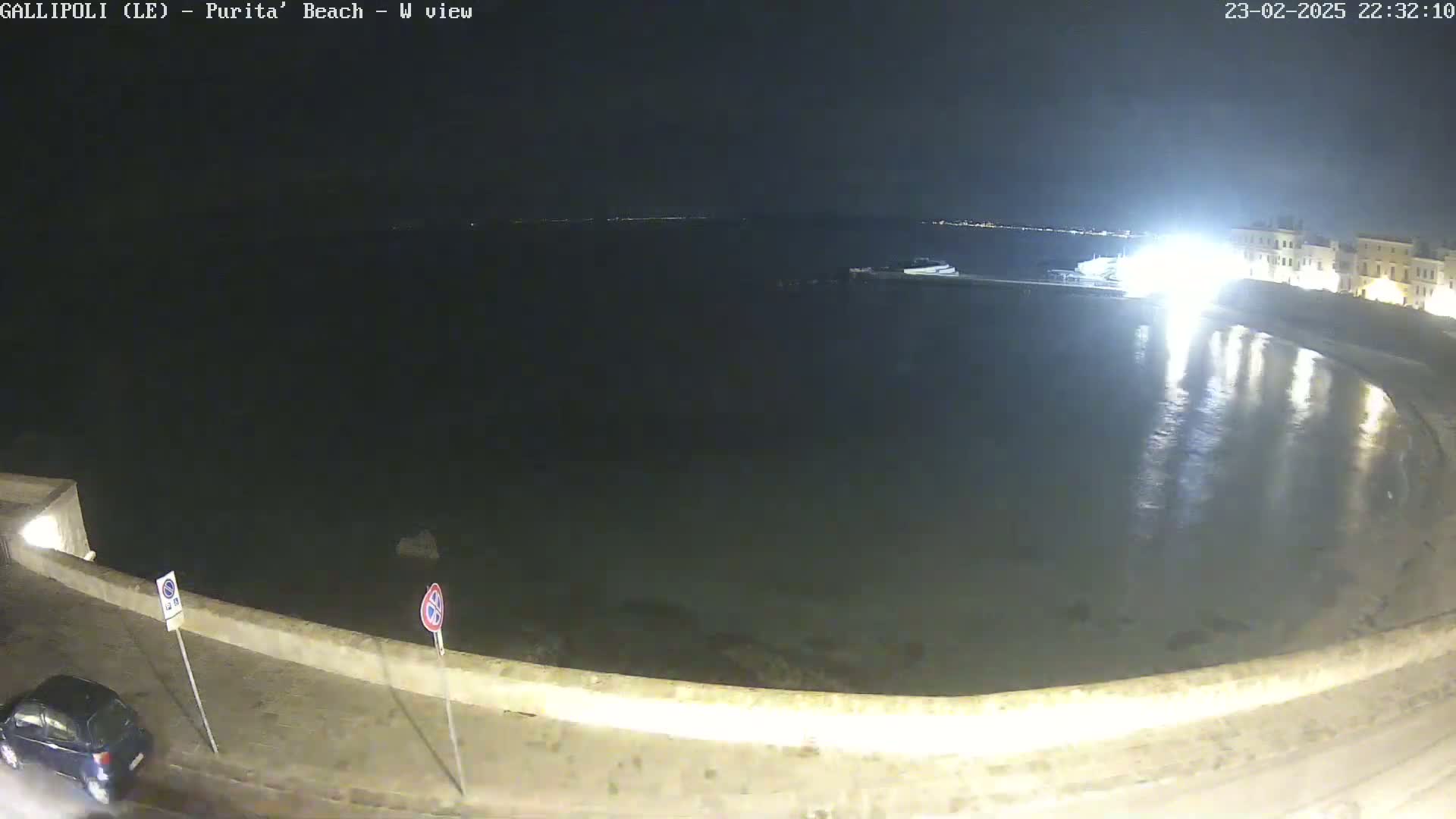 A nighttime view of a calm, dark body of water reflecting lights from buildings on the shore.