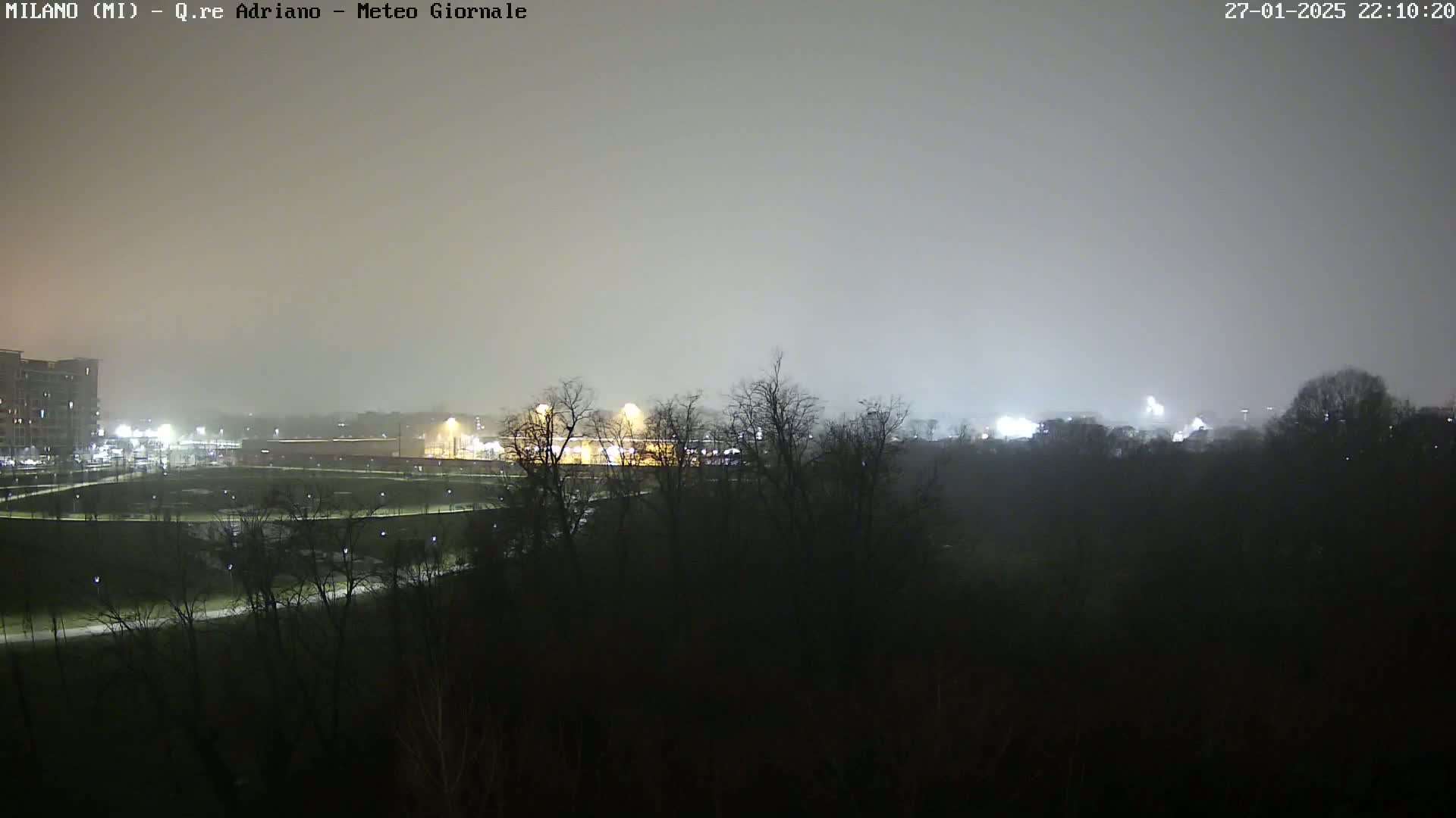 A nighttime view of a park and buildings in the distance, under foggy or hazy conditions.