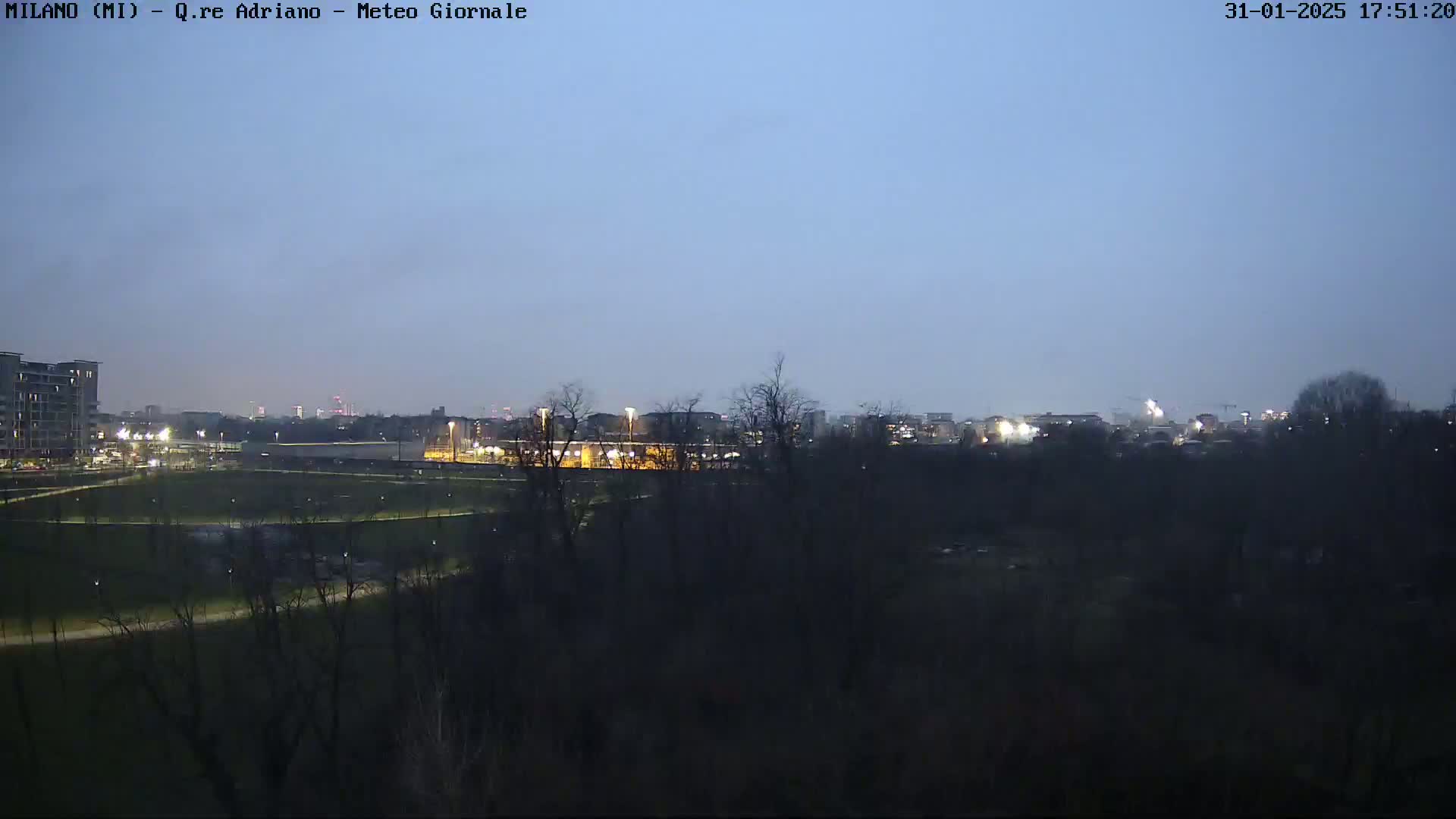 A twilight view of a park and city skyline, with a clear, dusky sky.