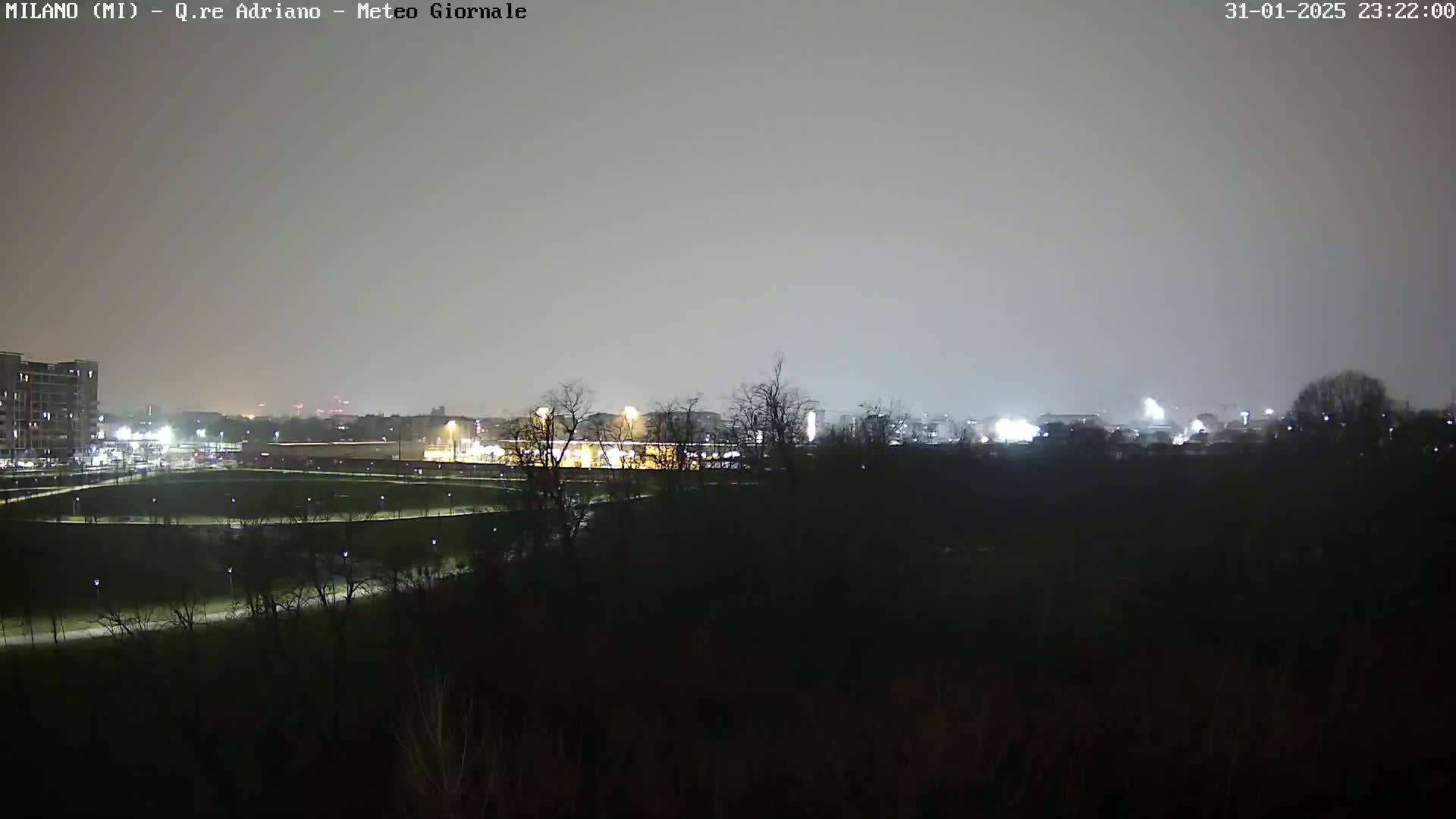 A nighttime view of a city skyline dimly lit under a hazy, overcast sky.