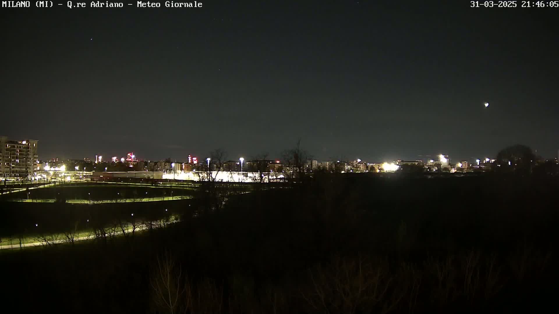 A nighttime view of a city skyline with a clear sky and a single bright object visible in the upper right corner.