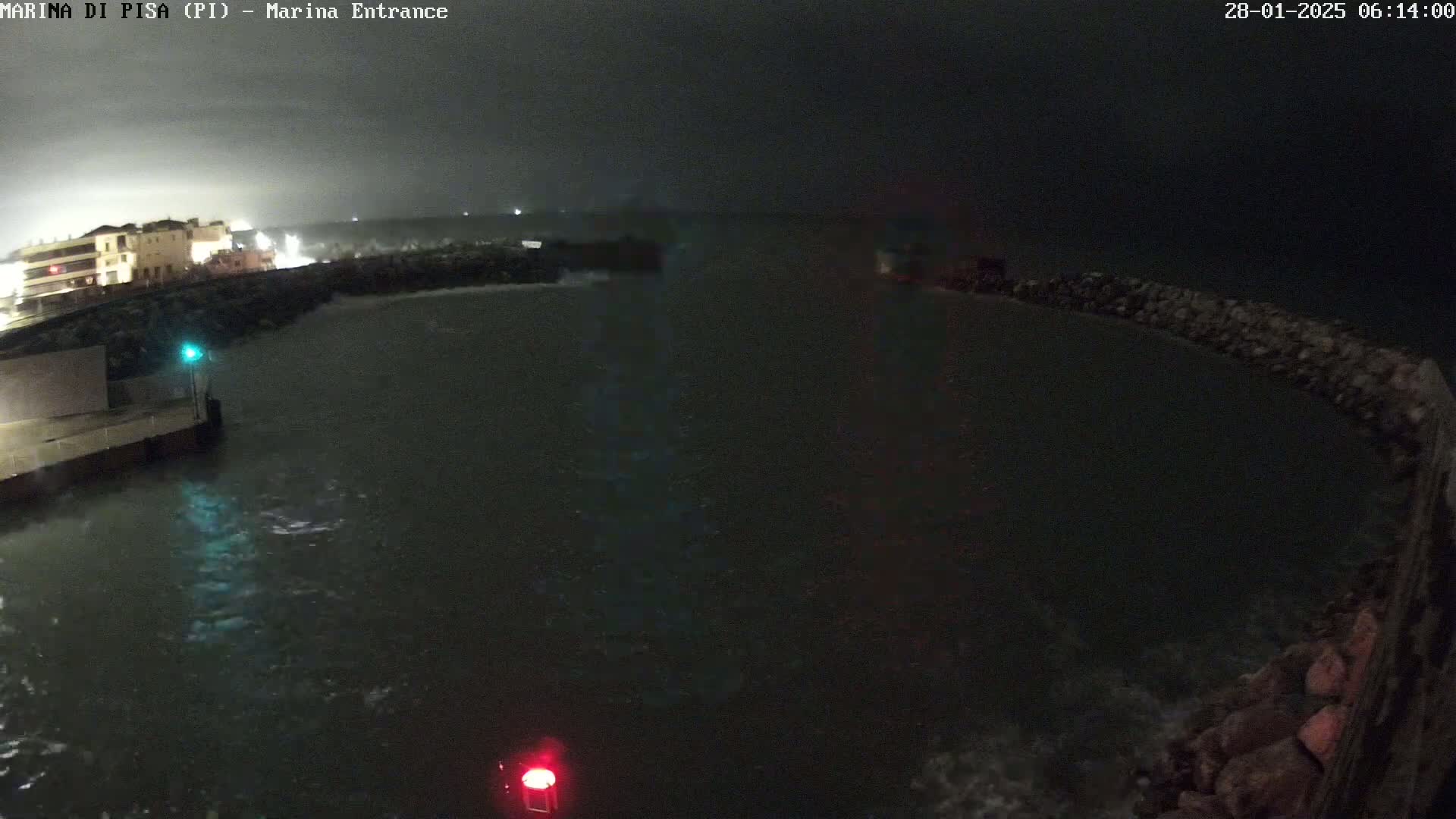 A nighttime view of a harbor entrance with choppy water under stormy conditions.