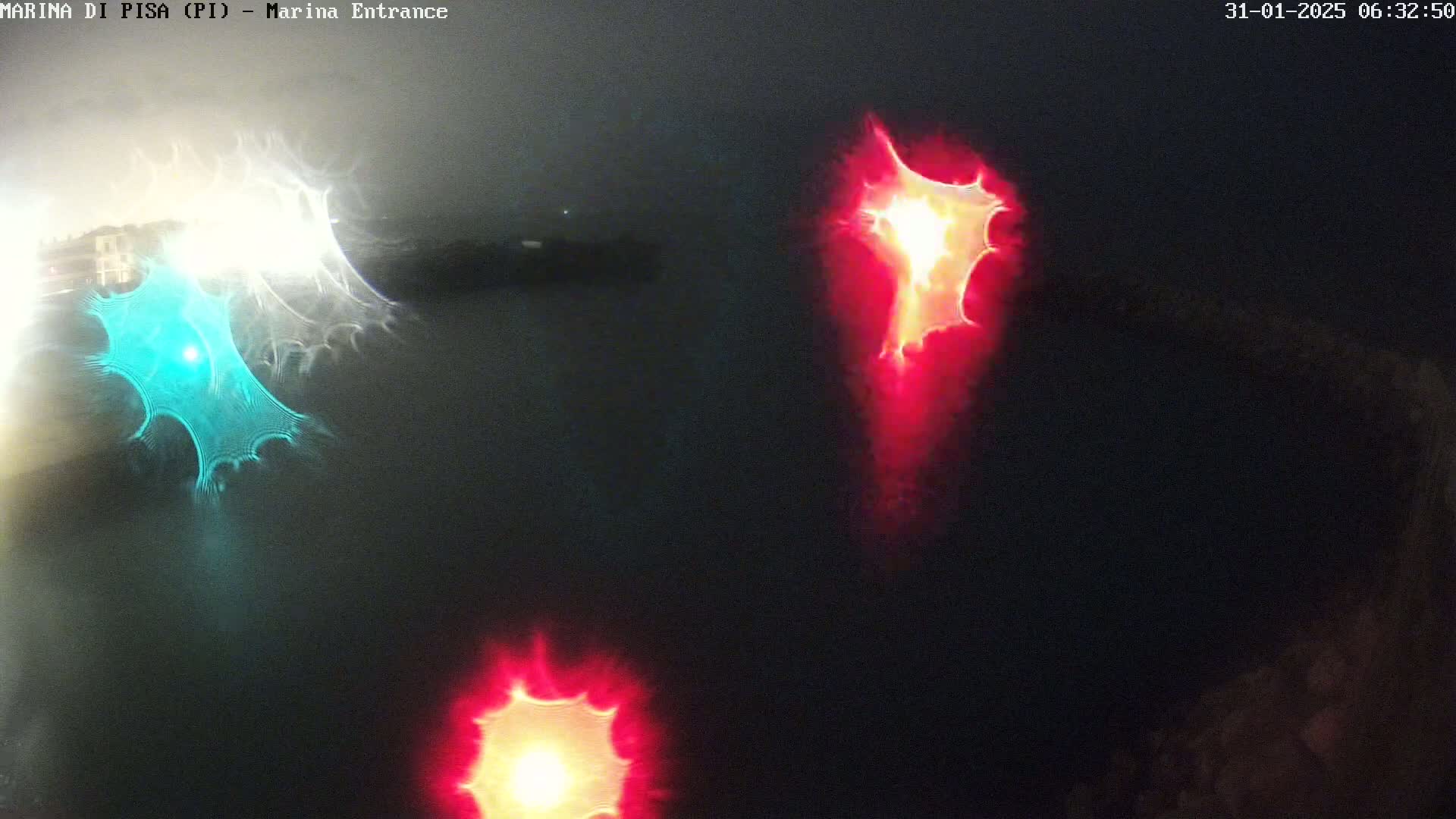 A nighttime image shows blurry, distorted lights in teal and red, possibly from vehicle headlights reflecting on water.