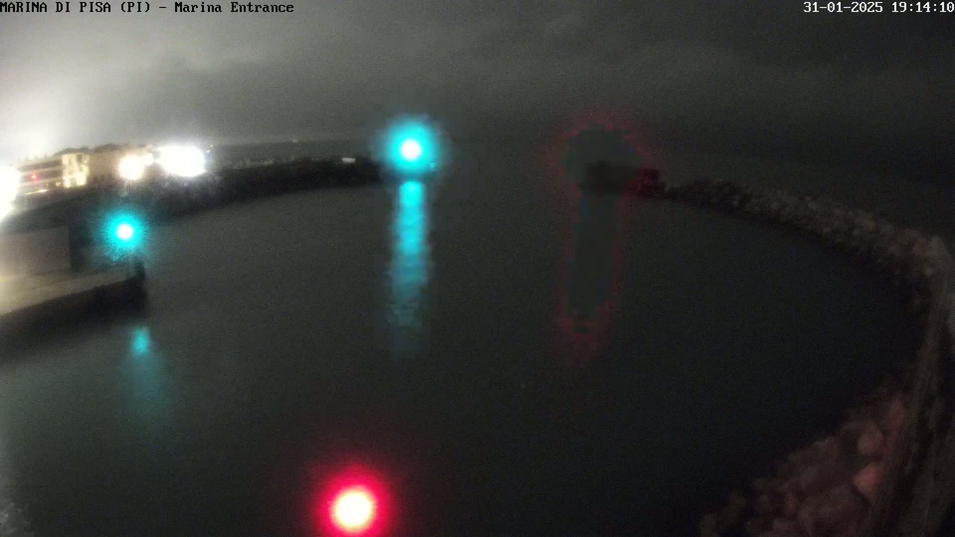 A nighttime view of a dark body of water with several lights reflecting on its surface, under a cloudy sky.