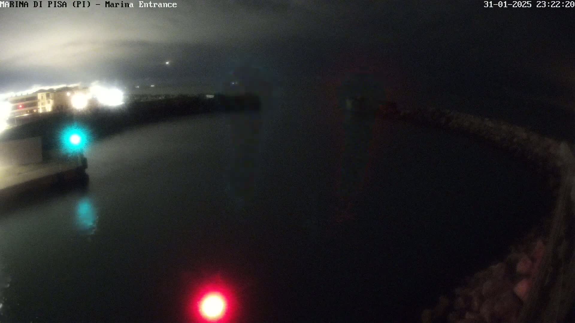 A nighttime view of a dark harbor with a single red and green light visible on either side of a body of water.