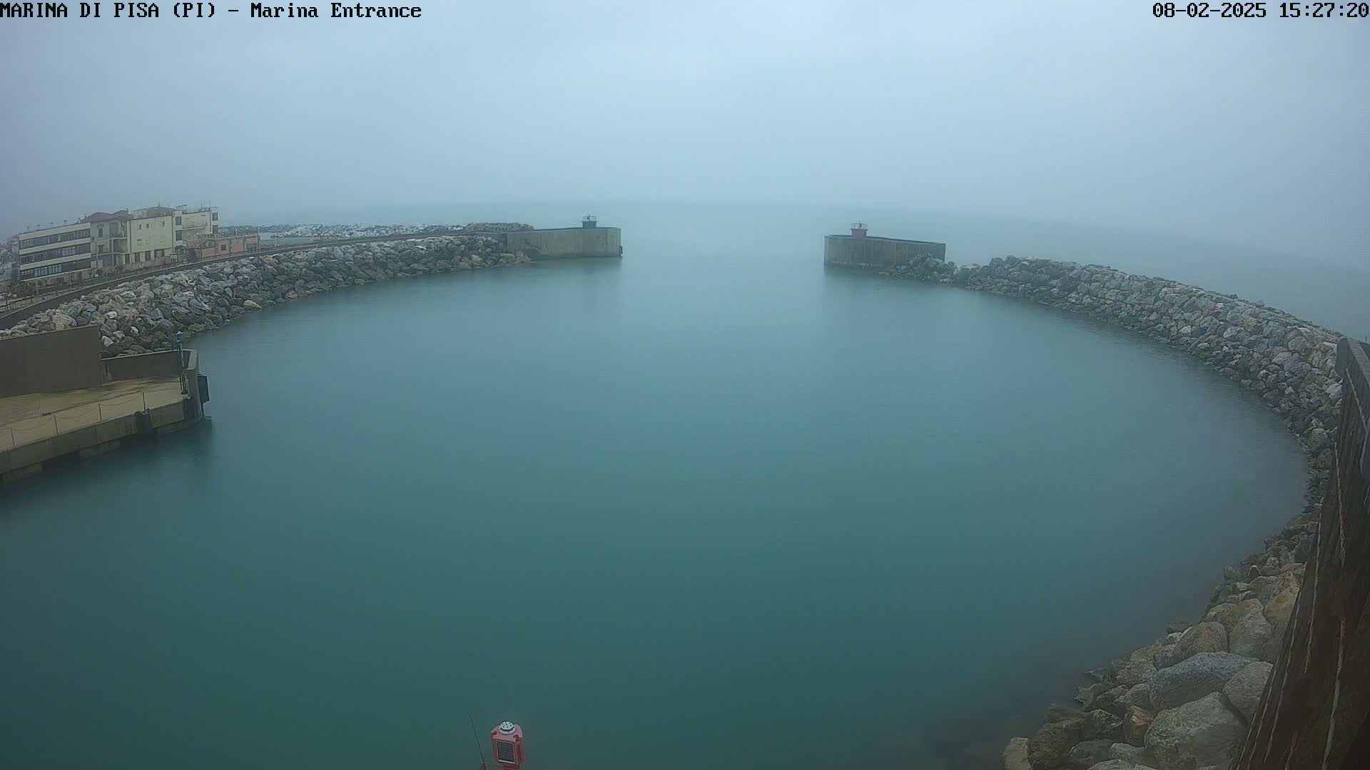 A foggy harbor entrance is shown, with calm, teal water enclosed by stone walls and a building visible in the distance.