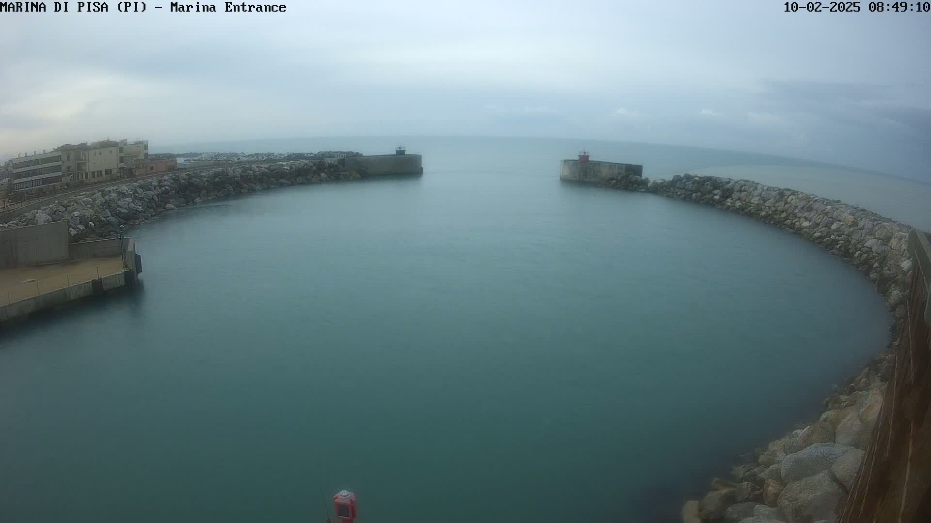 A harbor entrance with calm, greenish-blue water under an overcast sky.