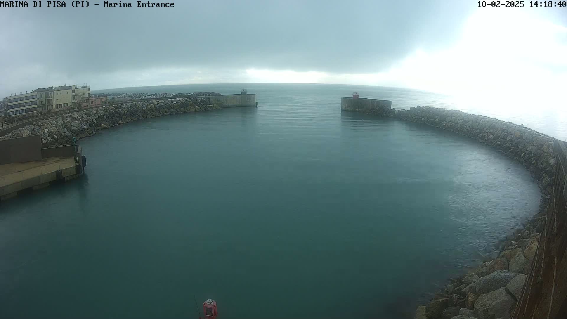 A marina entrance with calm, dark-green water under an overcast sky.