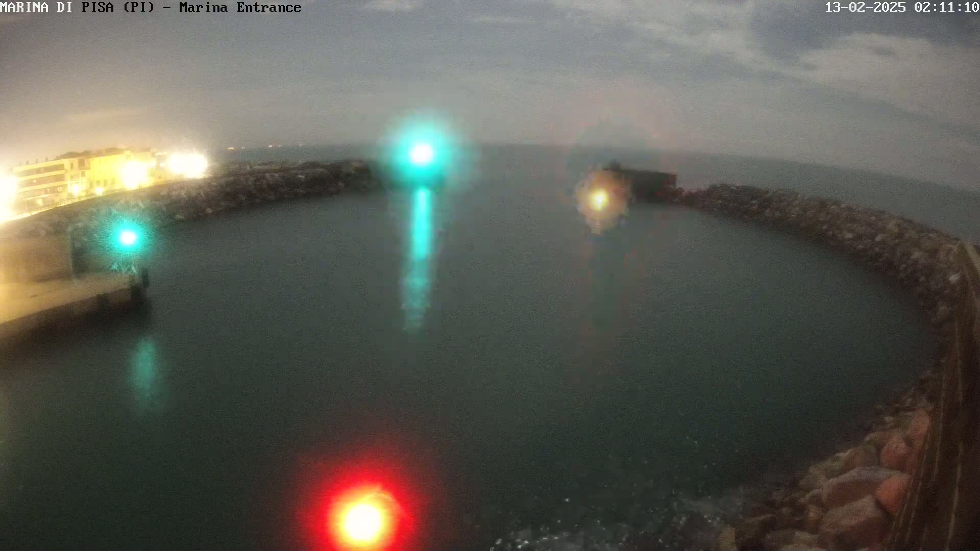 A nighttime harbor entrance is partially obscured by fog, with lights visible on the docks and in the water.
