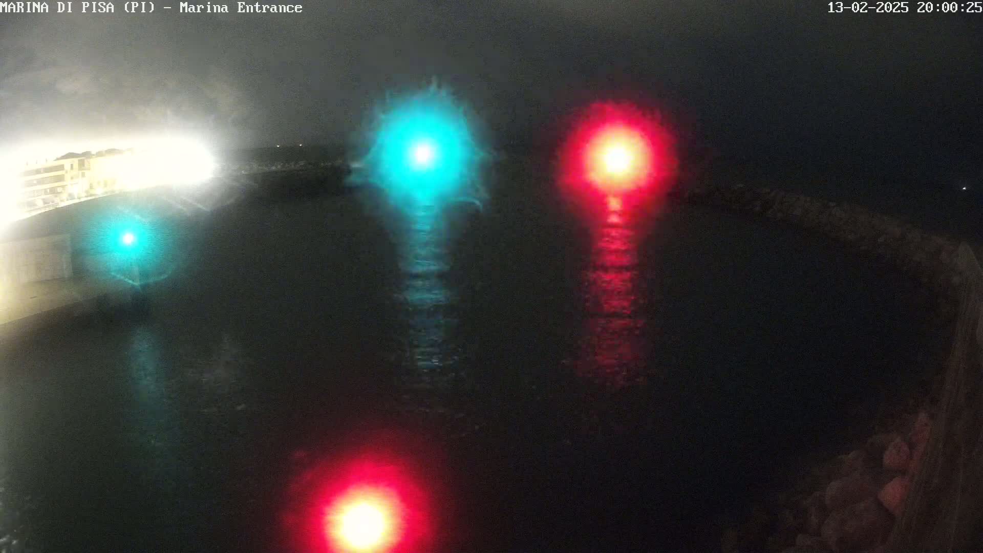 At night, a marina entrance is shown with three lights—one green and two red—reflecting on dark water.