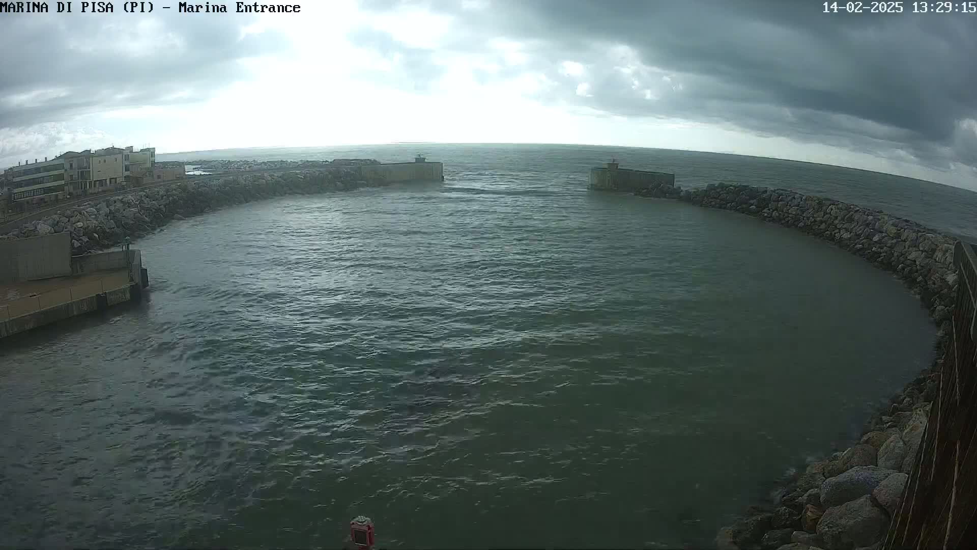 A harbor entrance with choppy water under a cloudy sky is seen from an elevated perspective.