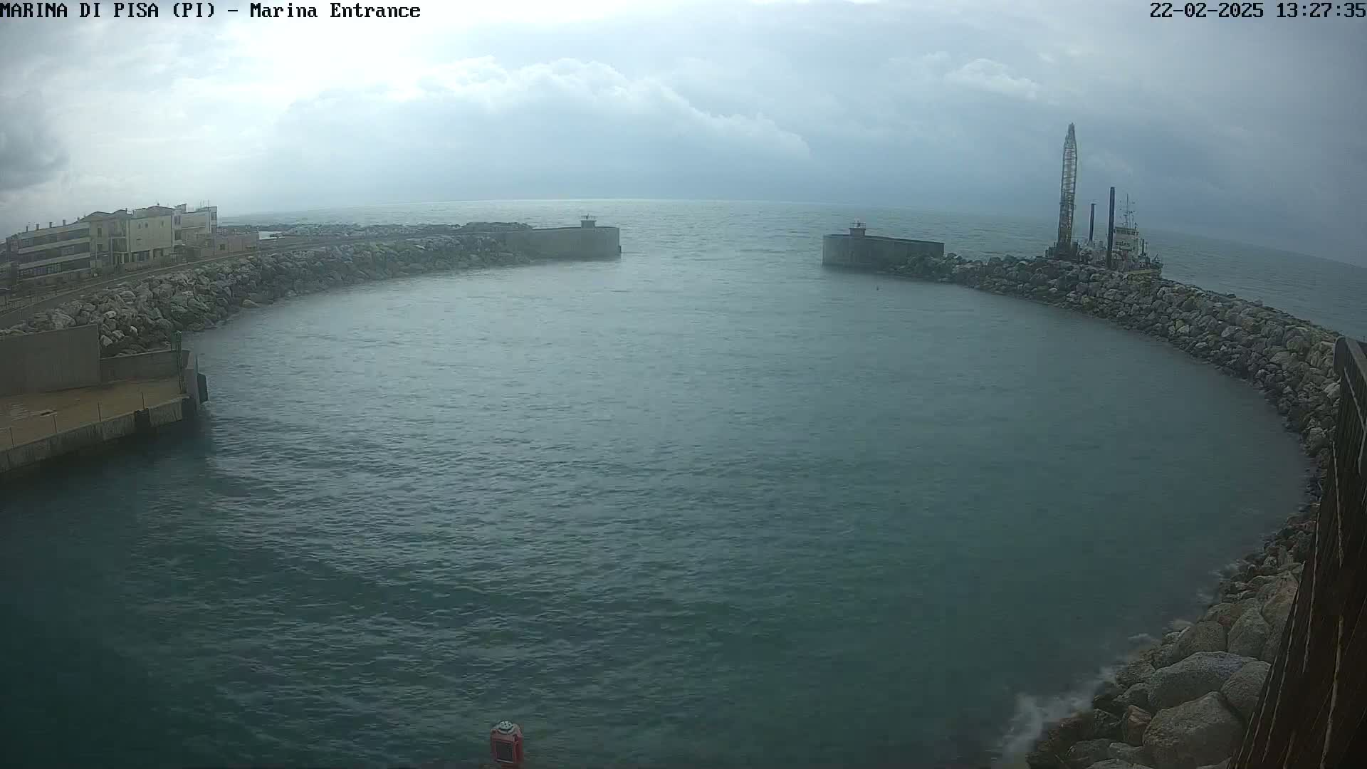 A harbor entrance with a partially cloudy sky and a construction vessel is visible on the right side.