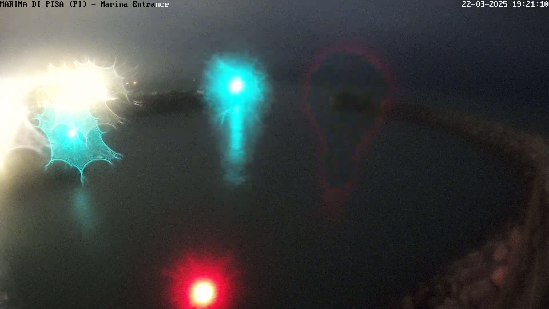A nighttime, blurry view of a dark body of water with bright, distorted lights reflecting on the surface.