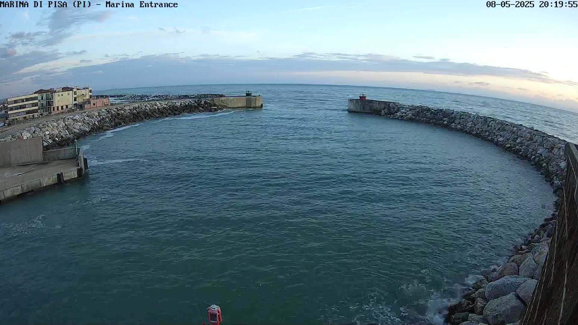 A calm, twilight sea surrounds a harbor entrance defined by stone walls and a small building on the left.