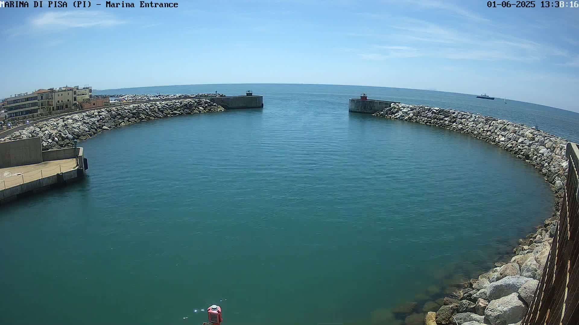 A harbor entrance with calm, teal water is partially enclosed by rock walls under a clear, sunny sky.