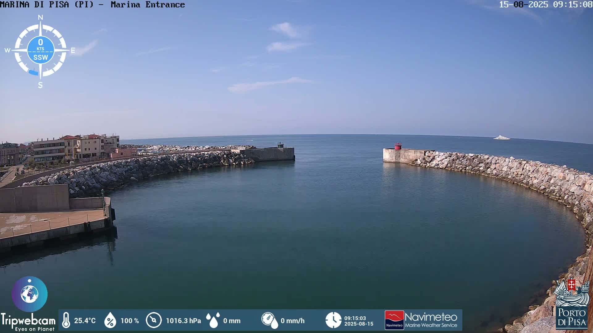 A harbor entrance with calm water under a clear blue sky shows a curved stone breakwater and a distant vessel.