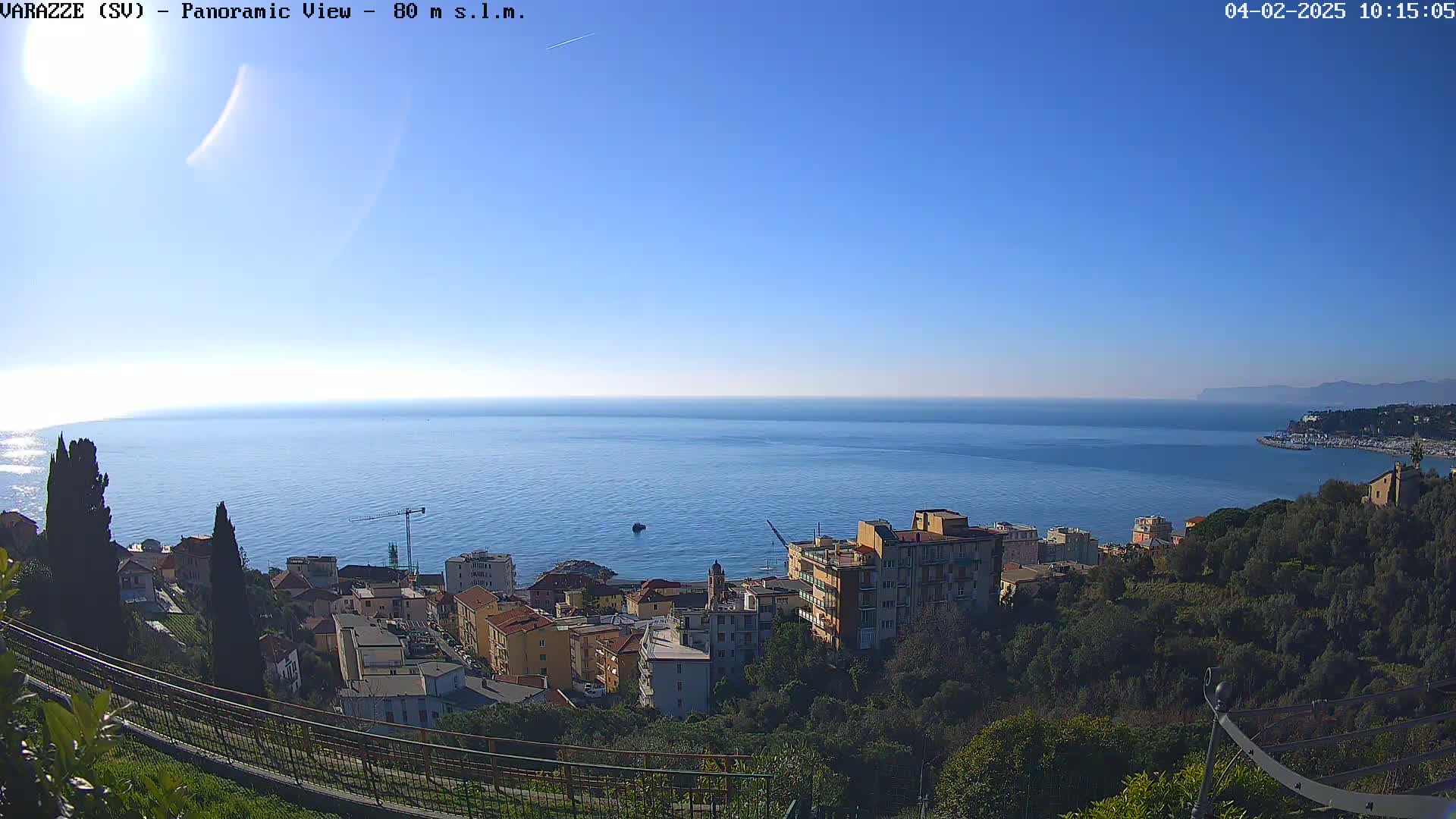 A coastal town overlooks a calm blue sea under a clear blue sky.